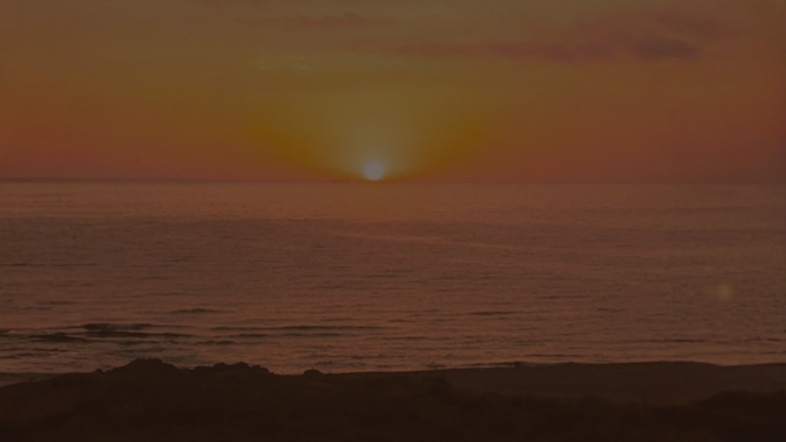The sun setting over the ocean at dusk